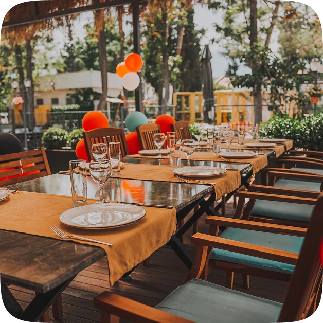 A long table set for a birthday party with balloons overhead