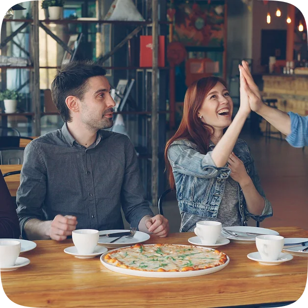 Two people celebrating over a shared pizza