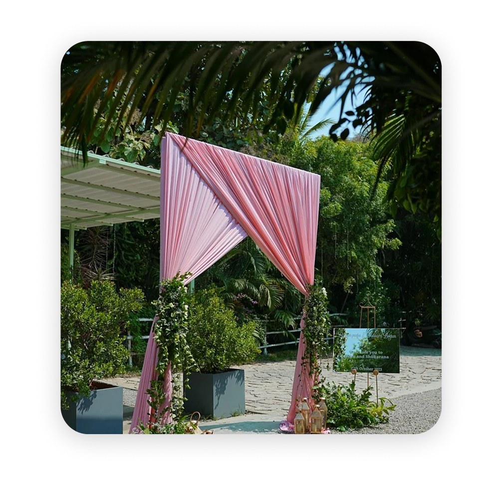 A pink draped arch set up in a garden